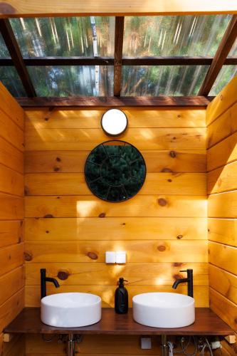 Baño con 2 lavabos en una pared de madera en Glamping - Projekt Alpaka, en Garbatka-Letnisko