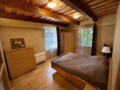 a bedroom with a bed and a dresser and windows at Vila Nidutė in Nida