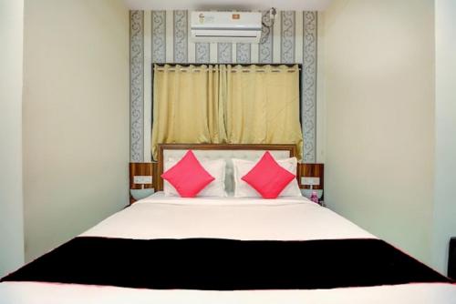 a bedroom with a bed with pink pillows at Hotel De Classico Juhu in Mumbai