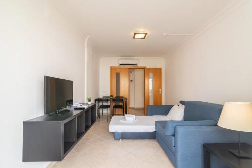 a living room with a blue couch and a television at Smy Santa Eulalia Algarve in Albufeira