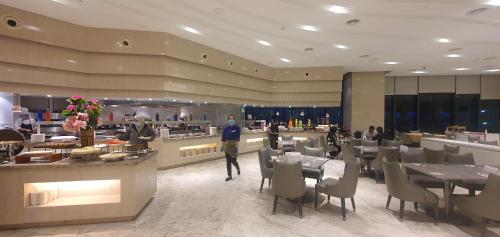 a restaurant with tables and chairs and a person standing in a room at Joyful Suite at Ion-Delemen Genting Highland in Genting Highlands