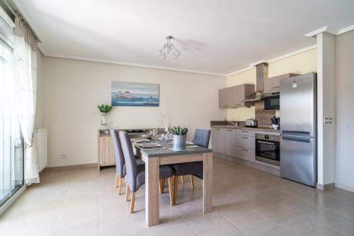 une cuisine et une salle à manger avec une table et un réfrigérateur dans l'établissement L'ANDALOU - Bel appartement standing avec terrasses en plein coeur dArcachon, à Arcachon