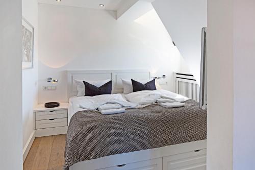 - une chambre blanche avec un grand lit blanc et des oreillers noirs dans l'établissement Beach House, à List auf Sylt