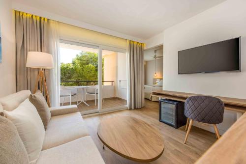 a living room with a couch and a tv at Valentin Somni Hotel & Suites in Paguera