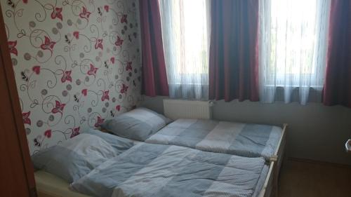 1 cama pequeña en un dormitorio con cortinas rojas en Réka Apartman, en Bük