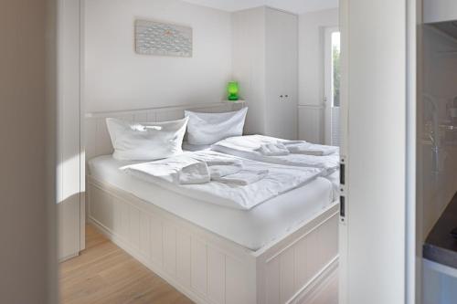 een wit bed met witte lakens en witte kussens bij Lister Eck 1 in List