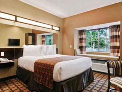 A bed or beds in a room at Microtel Inn & Suites by Wyndham Ozark