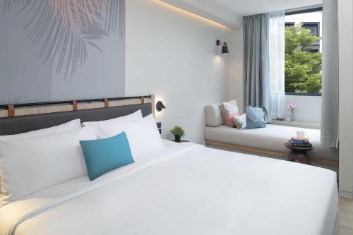 a bedroom with a large white bed and a couch at JonoX Phuket Karon Hotel in Karon Beach