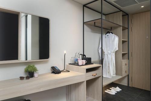 ein Ankleidezimmer mit einem Spiegel und einem weißen Bademantel in der Unterkunft JonoX Phuket Karon Hotel in Karon Beach