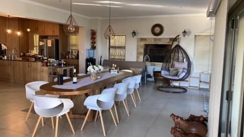a kitchen with a large wooden table and white chairs at Langebaan Golf Estate - Signature Hole 24hrs power in Langebaan