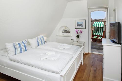 uma cama branca num quarto com uma televisão em Senenskiin em List