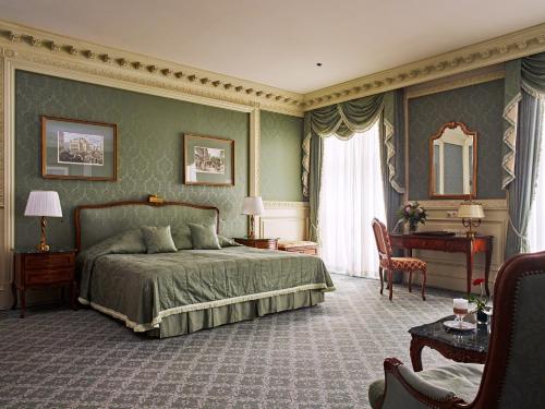 a bedroom with a bed and a chair and a table at Grand Hotel Wien in Vienna