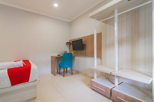 a bedroom with a bed and a desk and a blue chair at RedDoorz Plus @ Point Phila Cihampelas in Bandung
