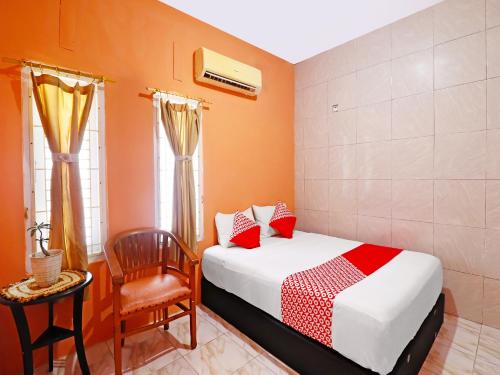 a small bedroom with a bed and a chair at OYO 91408 Kas Residence Syariah in Jambi