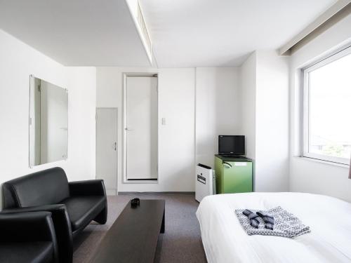 1 dormitorio con 1 cama, 1 silla y TV en Tabist THE GREEN ASAHIKAWA, en Asahikawa