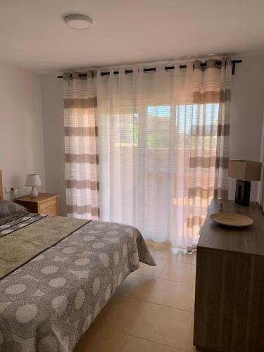 Schlafzimmer mit einem Bett und einem Fenster mit Vorhängen in der Unterkunft Luxury 2 bedroom 2 bathroom South facing second floor apartment in Los Martínez