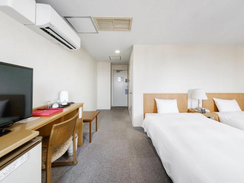a hotel room with two beds and a desk with a television at Tabist THE GREEN ASAHIKAWA in Asahikawa