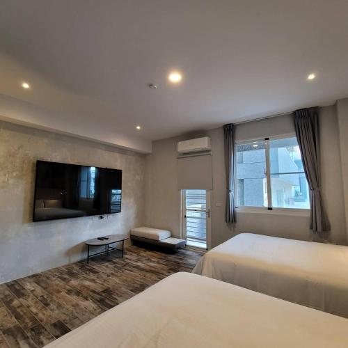 a bedroom with two beds and a flat screen tv at 芙蘿拉萃旅 in Taitung City