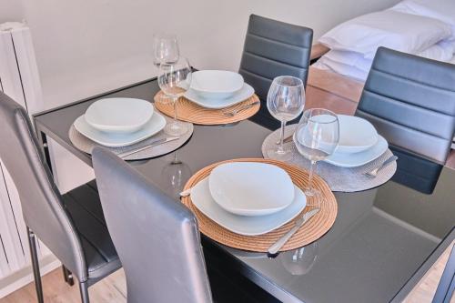 a dining table with plates and wine glasses on it at [MONZA-CENTRO] Modern Flat Near Train Station in Monza