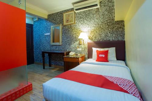 a bedroom with a bed with a red pillow and a desk at Super OYO Capital O 90125 Hotel Grand Orchard in Kuala Lumpur