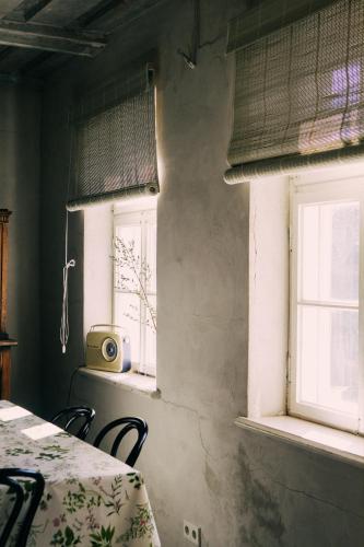 a dining room with two windows and a table and chairs at Kalnciema kvartāla Kuldīgas rezidence in Kuldīga