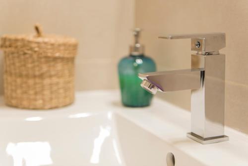 a bathroom sink with a faucet and a bottle of soap at B&B Villa Deseada in Periana