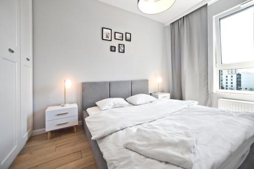 P&O Serviced Apartments Posag 7 Panien - Ursus في وارسو: غرفة نوم بيضاء مع سرير كبير ونافذة