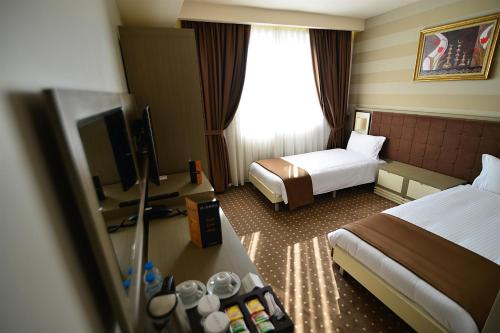 a hotel room with two beds and a television at Hotel Star Royal in Igdır