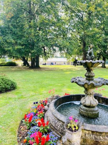 a fountain in the middle of a park with flowers at Walcot Hall - Stunning Stately Home set in 27 acres of parkland and sleeping 16+ in Alkborough