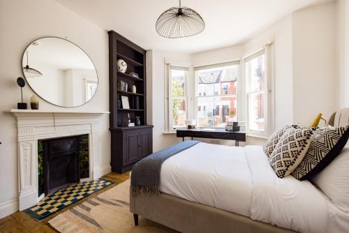 1 dormitorio con cama, espejo y chimenea en The Fulham Bolthole - Beckoning 2BDR Flat with Garden, en Londres
