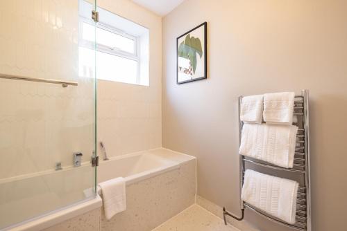 La salle de bains est pourvue d'une baignoire et d'une douche en verre. dans l'établissement The Fulham Bolthole - Beckoning 2BDR Flat with Garden, à Londres