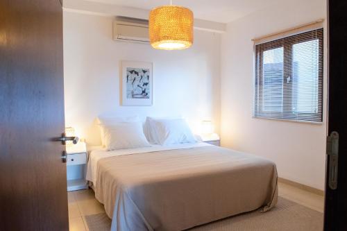 een slaapkamer met een wit bed en een raam bij Blauw Geluk in Blauw Baai