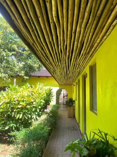 a yellow building with a wooden ceiling over a walkway at Baobab Village Studio in Dar es Salaam
