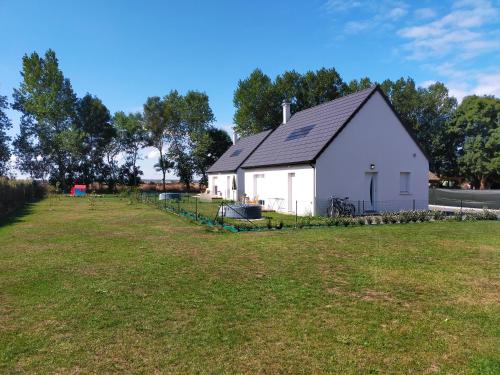 a white house with a large field in front of it at Maison individuelle neuve plein pied avec terrasse et jardin clos 10minutes a pied de la plage in Quiberville