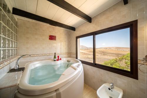 a bathroom with a tub and a sink and a window at Villa Pacios in San Bartolomé
