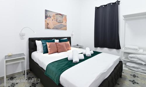 a bedroom with a large white bed with colorful pillows at Bazelet Apartments in Tiberias