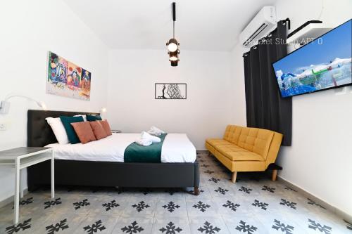a bedroom with a bed and a chair and a tv at Bazelet Apartments in Tiberias