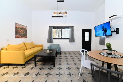 sala de estar con sofá amarillo y mesa en Puy Bazelet Apartments, en Tiberíades