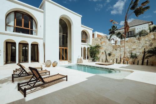 a house with a swimming pool and two benches at Casa Viamo in Canggu
