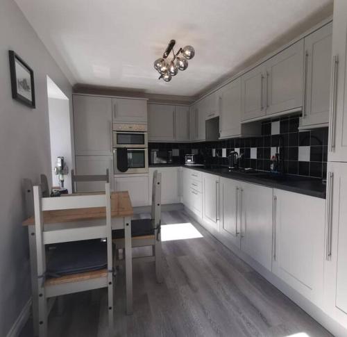 瑟索的住宿－B'Dazzled Flat, Castletown，厨房配有白色橱柜、桌子和用餐室。