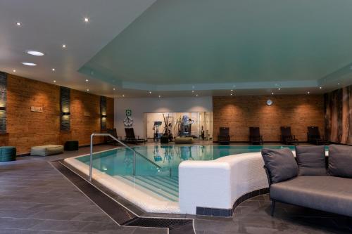 a pool in a hotel lobby with a couch and chairs at Hotel Forsthaus Nürnberg Fürth in Fürth