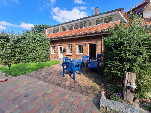 une terrasse avec des chaises bleues et une table en face d'une maison dans l'établissement Pension & Ferienhof Glüß, à Lünzen