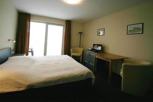 una camera d'albergo con letto, scrivania e finestra di Yachthafenresidenz-Wohnung-6205-832 a Kühlungsborn