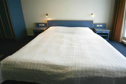 ein großes Bett in einem Zimmer mit zwei Nachttischen in der Unterkunft Yachthafenresidenz - Wohnung 6205 / 832 in Kühlungsborn