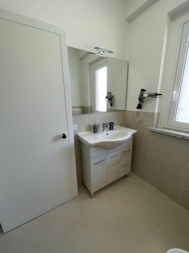 uma casa de banho branca com um lavatório e um espelho em AcquaChiara em Marina di Ragusa