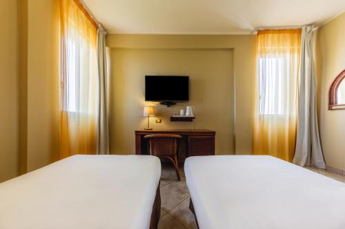 a hotel room with two beds and a television at Apulia Hotel Taranto Ara Solis in Lido Azzurro