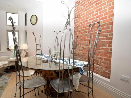 een eetkamer met een tafel en stoelen en een bakstenen muur bij The Sandpiper's Pearl in Nottage