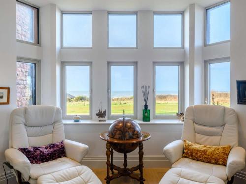 a living room with two chairs and a table and windows at The Sandpiper's Pearl in Nottage