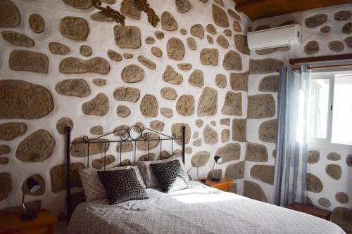 - une chambre avec un mur en pierre et un lit dans l'établissement Casa pitita, à Maspalomas