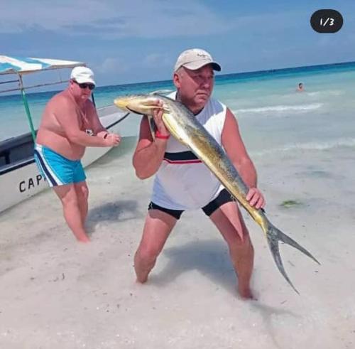 a man holding a fish on the beach at Casa Carlotta & Villa in Nungwi